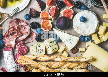 Close-up of wine snack set with meat variety, bread, green olives, figs, nuts and berries on wax paper, top view, horizontal com Stock Photo