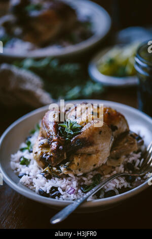 One roasted game hen served on top of black bean rice is photographed from the front view Stock Photo