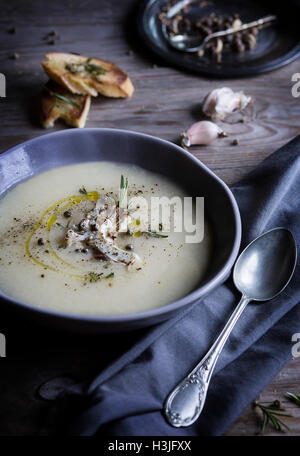 Cauliflower cream soup in bowl with grilled bread slices on wooden table Stock Photo