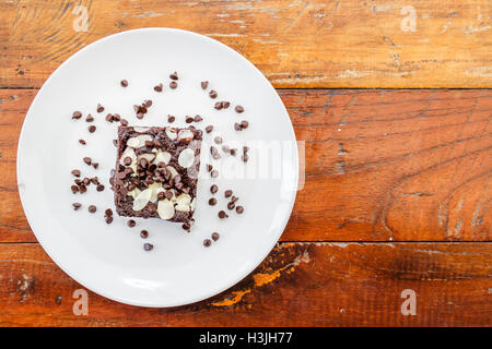 Brownies topped with almonds on a white plate on a wooden table in a restaurant.top view. Stock Photo