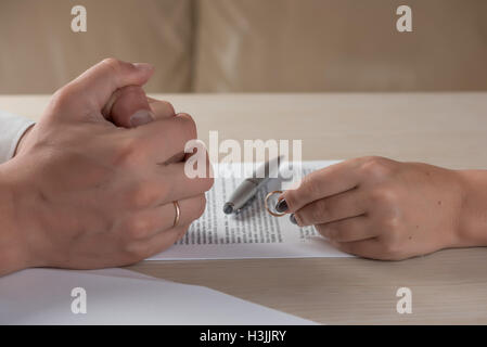 Wife and husband signing divorce documents, woman returning wedding ring Stock Photo