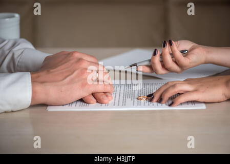 Wife and husband signing divorce documents, woman returning wedding ring Stock Photo