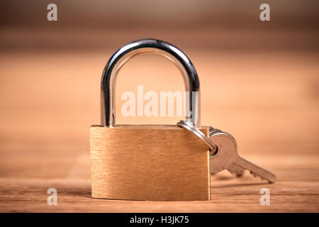 Golden or bronze Padlock and keys on a brown wooden oak table Stock Photo