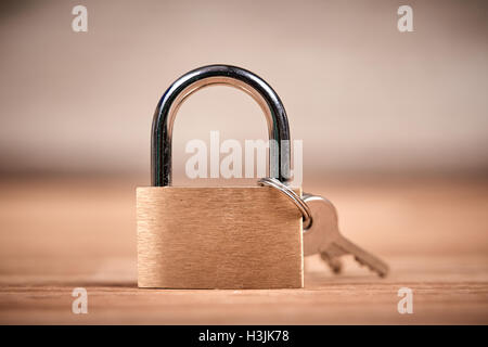 Golden or bronze Padlock and keys on a brown wooden oak table Stock Photo