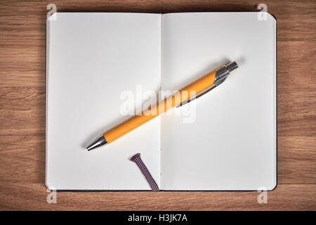 Open notebook and yellow pen ballpoint on a brown wooden table Stock Photo