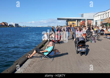 People are enjoying summer at the waterfront on Papirøen, Paper Island, outside the new street food eatery, Christianshavn. Copenhagen Street Food. Stock Photo