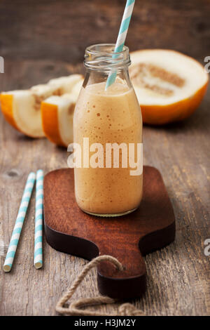 melon  smoothie in a glass bottle, melon slices  on the old wooden background Stock Photo