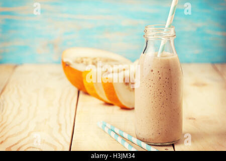 melon  smoothie in a glass bottle, melon slices  on the  wooden background Stock Photo