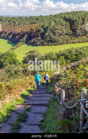 Two walkers descending the footpath from Golden Cap summit (highest point on south coast) above Seatown, Dorset, England, UK Stock Photo