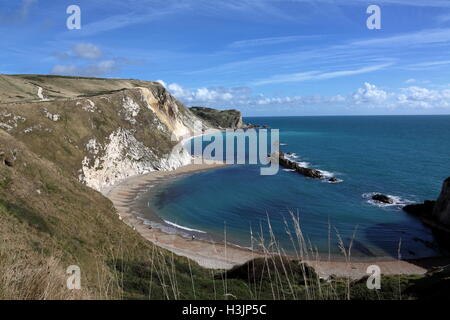 Looking across man of war bay at the patterns created by the tidal flow on the sand and shingle beach with white chalk cliffs. Stock Photo