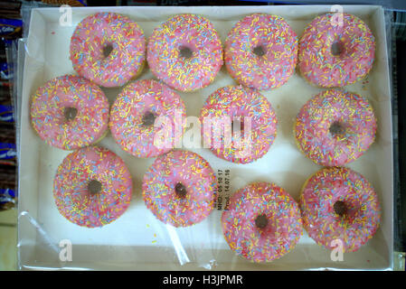 Boxed  dozen pink icing with rainbow sprinkles dough rings, dough nuts in cellophane wrapping unbranded, Stock Photo