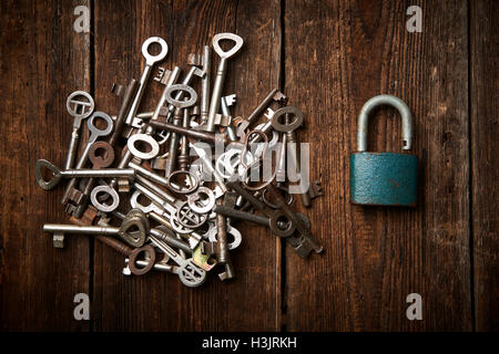 Group of old rusty padlocks with pile of keys on brown wooden table Stock Photo