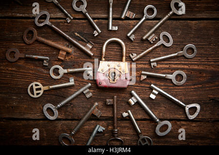 Vintage rusty padlock surrounded by old keys on a weathered steel background Stock Photo