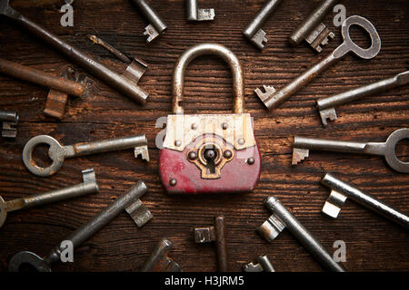 Vintage rusty padlock surrounded by old keys on a weathered steel background Stock Photo