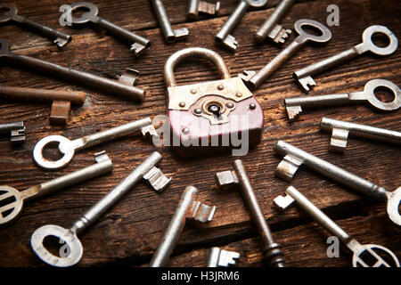 Vintage rusty padlock surrounded by old keys on a weathered steel background Stock Photo