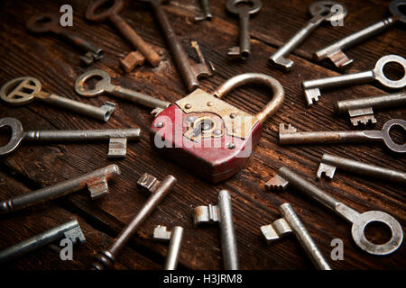 Vintage rusty padlock surrounded by old keys on a weathered steel background Stock Photo