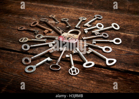 Vintage rusty padlock surrounded by old keys on a weathered steel background Stock Photo