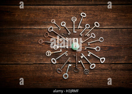 Vintage rusty padlock surrounded by old keys on a weathered steel background Stock Photo