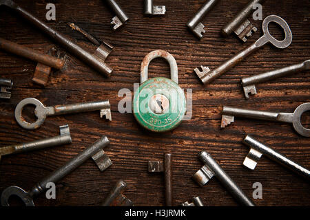 Vintage rusty padlock surrounded by old keys on a weathered steel background Stock Photo