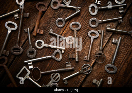 many different keys on brown wooden background. Stock Photo