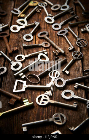 many different keys on brown wooden background. Stock Photo