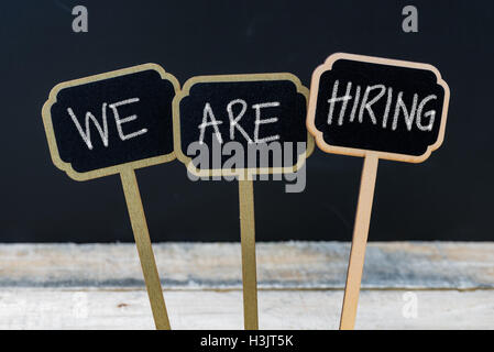 Business message WE ARE HIRING written with chalk on wooden mini blackboard labels Stock Photo