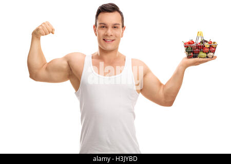 Man flexing his bicep and holding a small shopping basket full of fruits and vegetables isolated on white background Stock Photo