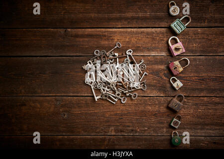 Group of old rusty padlocks with pile of keys on brown wooden table Stock Photo