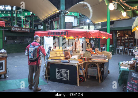 Borough Market, London UK Happy seller young man and woman in a cheese stand serving a customer Stock Photo