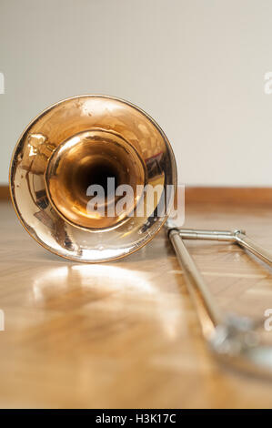 Trombone bell on brown wooden parquet, bell detail selective focus Stock Photo