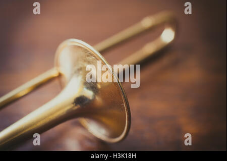 Trombone bell on brown wooden parquet, bell detail selective focus Stock Photo