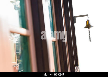 Brass bell in front of old wooden building, isolated on white background Stock Photo