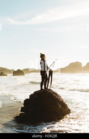 Diver with speargun standing on rock, Big Sur,  California, USA Stock Photo
