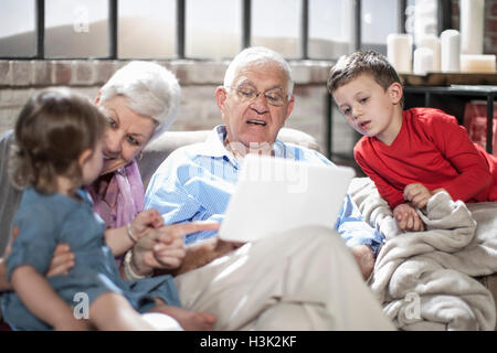 Grandparents playing with grandchildren, using digital tablet at home Stock Photo