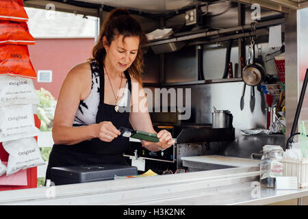 Woman using smartphone card reader for payment at food stall trailer Stock Photo