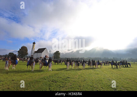 Women and men dressed in traditional garb sit on horses wearing festive decorations in front of the St. Coloman's Church in Schwangau, Germany, 09 October 2016. They are taking part in the St. Coloman's celebrations, observed on the second Sunday of October every year. Riders join a procession and a church service during which the horses are blessed. As legend will have it, the Irishman Coloman is said to have taken a rest, preached and tended to cattle in Schwangau on his pilgrimage from Ireland to Jerusalem. Photo: KARL-JOSEF HILDENBRAND/dpa Stock Photo