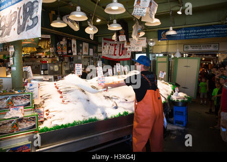 Fish monger throwing ice over fish for sale at Pike Place Fish Market - Seattle, WA Stock Photo