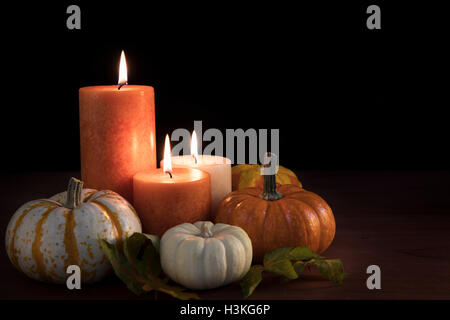 Three candles surrounded by gourds with black background and space for copy. Stock Photo