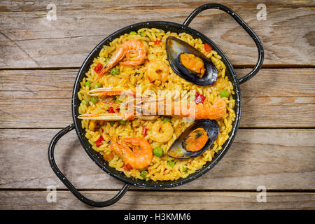 Spanish paella on a wooden table with shrimps, mussels, shellfish, prawns and norway lobsters Stock Photo