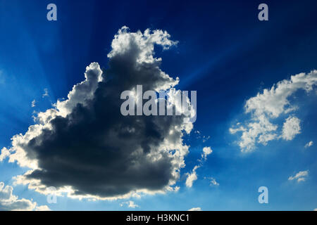 Blue sky with sunbeams shining through the dark cloud. Stock Photo