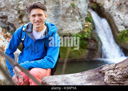 Portrait of handsome male Hiker sitting tree trench at lake Stock Photo