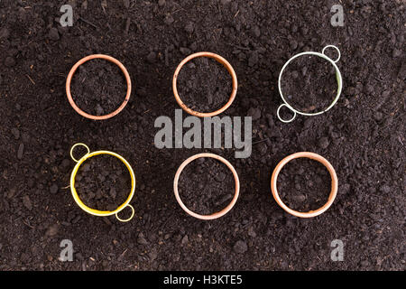Six neatly arranged planters filled with rich fertile soil with four terracotta flowerpots and two colorful pails ready for plan Stock Photo