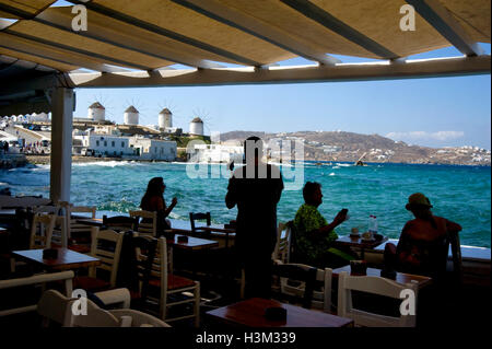 View of windmills from seaside cafe in Mykonos, Greece Stock Photo