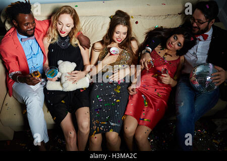 Relaxed friends with drinks having rest on sofa Stock Photo