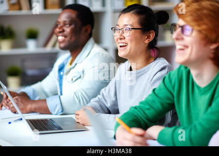 Happy intercultural students looking at spokesperson during presentation Stock Photo