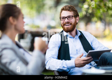 Two young co-workers discussing project outdoors Stock Photo