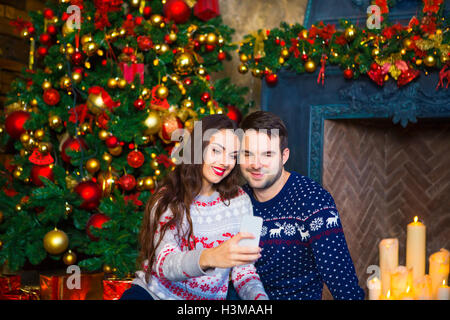 Young couple near fireplace celebrating Christmas. Love and relationship concept. Stock Photo