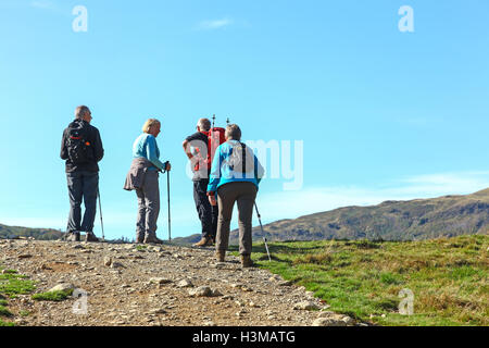 Four elderly walkers reaching the summit of a hill in the English Lake District Cumbria England UK Stock Photo