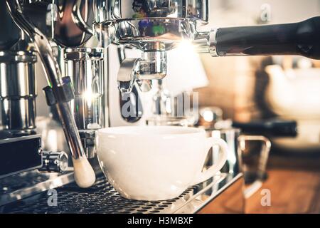 Espresso Coffee Machine in Action. White Coffee Cup Under Professional Portafilter. Stock Photo