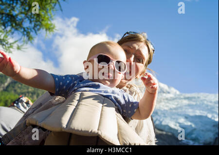 Low angle view of baby girl in sling sticking tongue out at camera Stock Photo